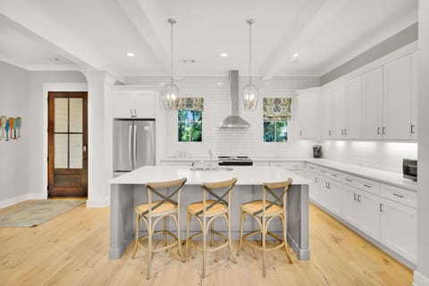 The kitchen offers ample counter space, stainless steel appliances, is fully stocked, and includes three barstools for additional seating.