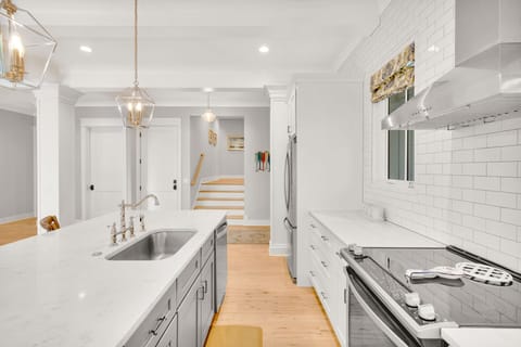 The kitchen offers ample counter space, stainless steel appliances, is fully stocked, and includes three barstools for additional seating.