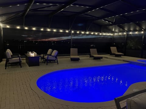 Resort style private pool featuring a fire table, luxury loungers and lights all around the pool!