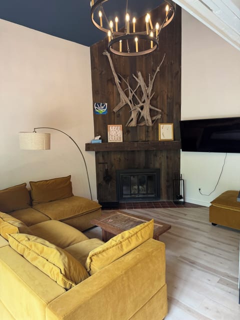 Living room with pit sectional, smart TV, and a traditional fireplace