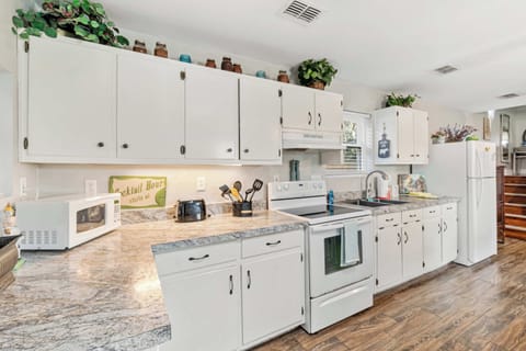 Bright, fully equipped kitchen with white cabinets and ample counterspace.