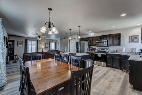 Kitchen with full complement of stainless steel appliances, cookware, bakeware, and large dining room table with seating for 8-10 people. 
