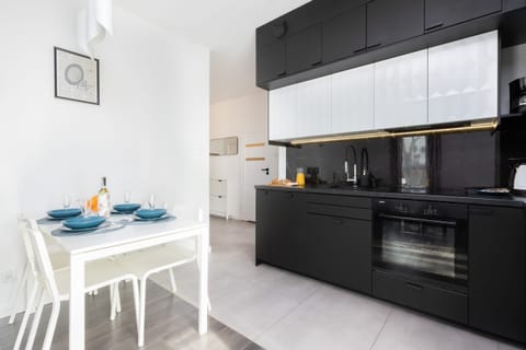 A sleek, modern kitchen with black and white cabinets, an adjoining dining area with a set table for two.