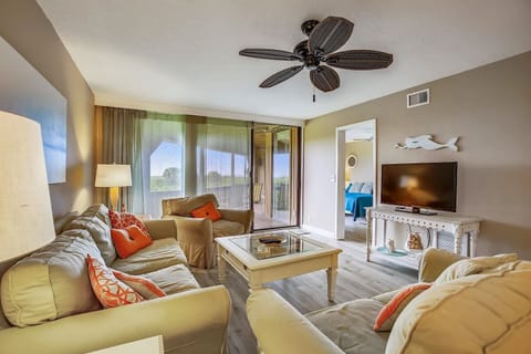 - Relax in the inviting living room with plush sofas, coastal decor, and a flat screen TV
- Large sliding doors open to the balcony, filling the space with natural light
- Ceiling fan and warm tones create a cozy yet breezy beach retreat
