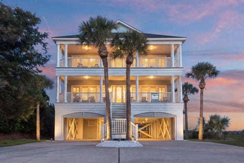 Balconied beach house lit at dusk at Wicker Cottage, a 7-bedroom oceanfront rental from Thomas Beach Vacations