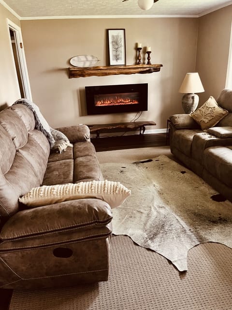 Living room with five reclining seats, electric fireplace, and large windows
