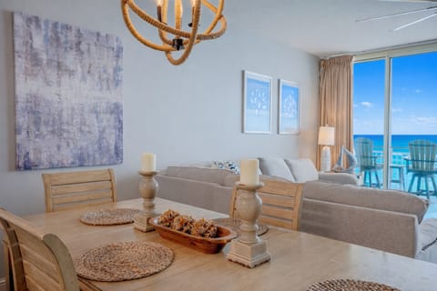 Wood dining table set with coastal décor, opening into the living room with ocean views.