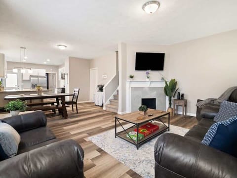Step into this open-concept living area with cozy leather sofas, a stylish coffee table, and a modern fireplace topped by a wall-mounted TV. The space flows seamlessly into a dining area and bright kitchen for effortless entertaining! ️️