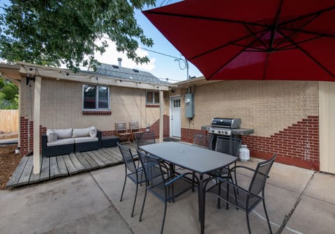 Backyard patio includes a propane grill and outdoor seating with large umbrella