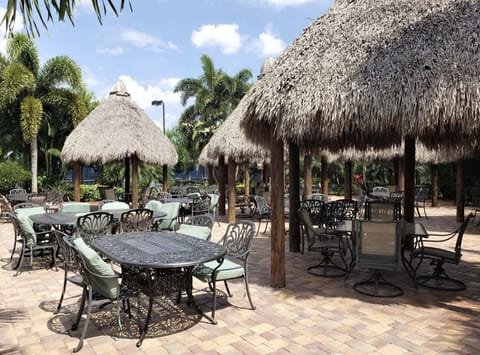 Common area near pools & clubhouse with tiki huts, grills, dining table & chairs
