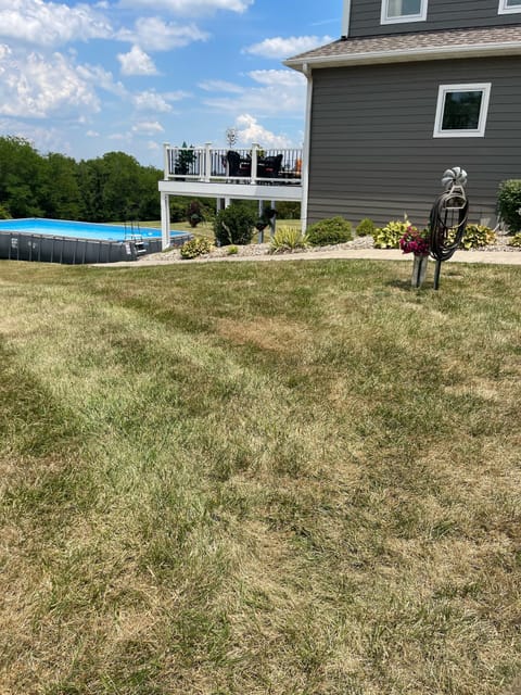 Side view of home, pool, deck, and patio with hot tub.