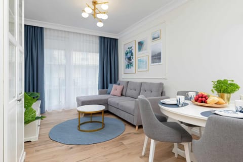 Dining area with a round table, soft gray chairs, and elegant decor in a bright space.
