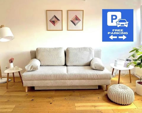 Modernes, lichtdurchflutetes Wohnzimmer mit gemütlichem Zweisitzer-Schlafsofa, stilvollen Beistelltischen und sanften Naturtönen. Ideal zum Entspannen.