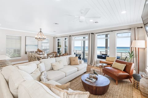 Sink into plush sofas while ocean waves sparkle through floor-to-ceiling windows in your bright, coastal living space.