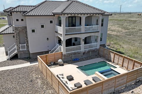 Modern coastal retreat with private pool and hot tub, surrounded by natural landscape and open skies.