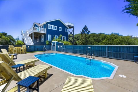 A large fenced-in pool deck area features an inviting private pool and plenty of chairs and pool loungers to make tanning poolside a breeze.