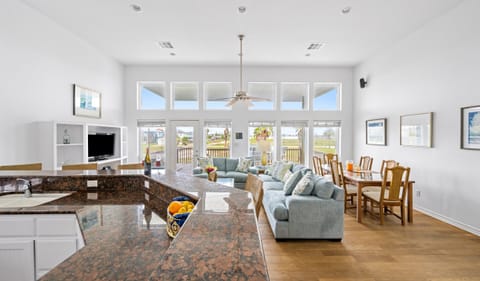 Open Plan Living — Granite Kitchen Bar, Blue Sofas & Wall of Windows with Palm Views