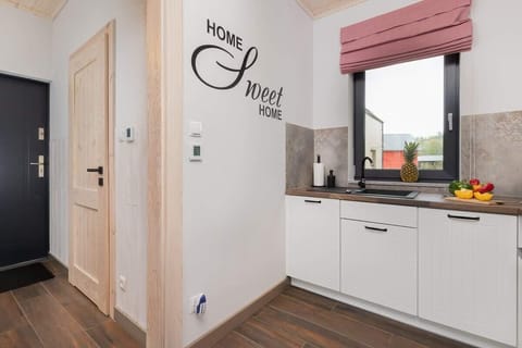 A small kitchen setup with a coffee maker, cutting board, and vegetables displayed on the counter.