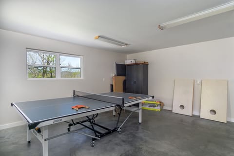 Game room in the garage with ping-pong table & cornhole.