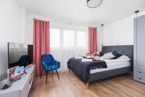 Modern and atmospheric living area with television, stylish blue chair, capacious wardrobe and comfortable double bed.