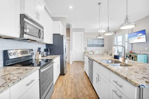 Well-equipped kitchen with custom cabinetry, backsplash, stainless appliances including side by side refrigerator. 