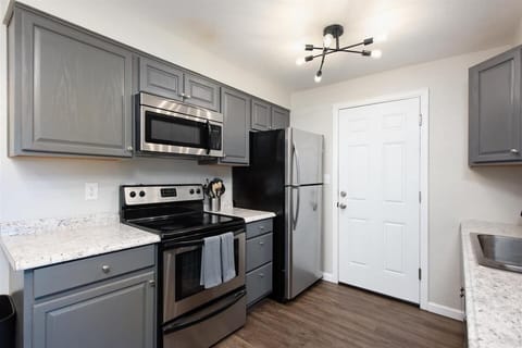 The kitchen features beautiful countertops and modern appliances, including refrigerator, stove, oven, microwave and coffee maker.