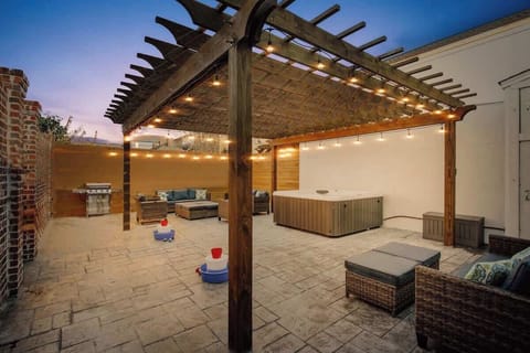 Spacious backyard oasis with a pergola, string lights, hot tub, and outdoor seating. Perfect for relaxing evenings, grilling, or gathering with friends in a private, beautifully designed setting.