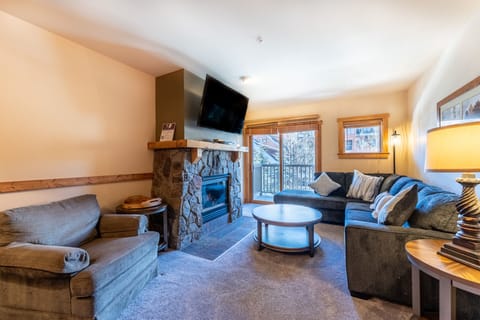 Sink into plush sofas by your stone fireplace while mountain views frame your cozy living space perfectly.