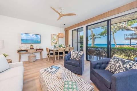 Bright living room with sliding doors opening to ocean views, furnished with cozy seating and a dining area in the background