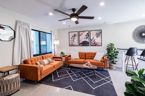 Modern living room with vibrant orange sofas and contemporary artwork.