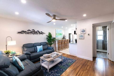 Modern living room with leather sofas and an open kitchen bar area.