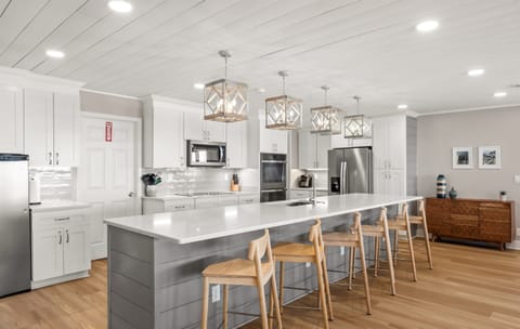 Six barstools complete the function of the 13+ foot quartz countertop and island. A high chair and baby gate are located in the utility closet just behind the ovens.
