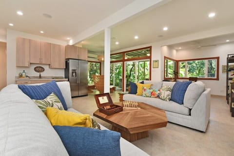 Bright open downstairs second living area with kitchen modern sofas, tropical décor, flat screen TV and lush garden views.