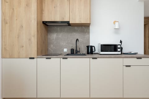 An open kitchen with minimalist design. The light wood cabinets and white countertops create a clean, modern aesthetic.