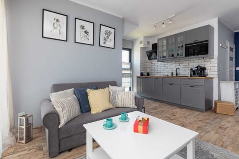 A cozy living area featuring a grey sofa, wooden coffee table, and neutral decor. Framed artwork adds a modern touch.
