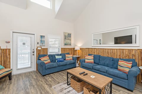 Relax in your bright living space with comfortable blue sofas, vaulted ceilings, and warm bamboo accents that create a coastal-inspired atmosphere.