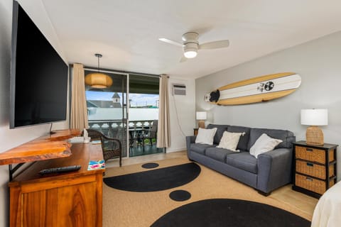 Kick back in your coastal-inspired living room with surfboard art and a cozy sofa, where ocean breezes drift through the balcony and a flat-screen TV awaits your favorite shows.