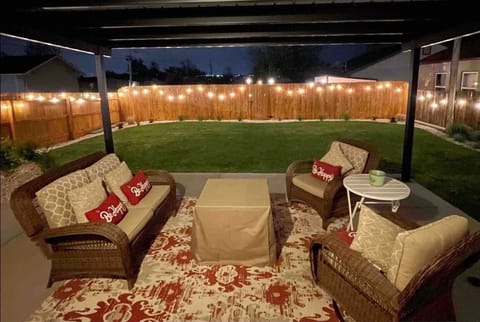 Large covered backyard patio with comfy furniture gas fire pit and cafe lighting