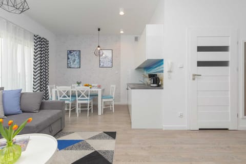 A modern open-concept living area with light-colored flooring, a sofa, and stylish curtains. The combination of blue and gray creates a calm atmosphere.