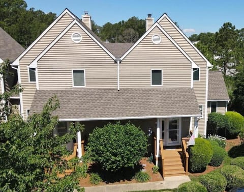 541D Hudson Avenue - Front Exterior Elevation - his charming multi-level coastal townhome features classic cedar-shake style siding and architectural gables. The entrance is framed by lush, mature landscaping and professional greenery, creating a welcoming and private feel for guests arriving at their vacation retreat.