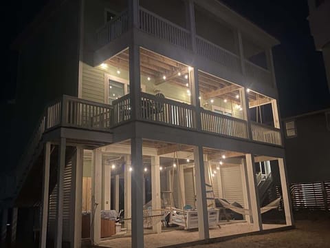 Evening fun zone with jacuzzi, fire pit, and porch swing—your home at night