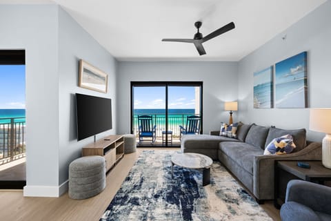 Relax in your bright living room where ocean views stretch endlessly beyond your private balcony, creating the perfect beachside retreat.