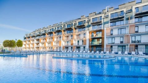 A scenic view of a luxurious outdoor swimming pool, surrounded by modern apartments. The pool area is well-maintained and perfect for relaxing or swimming.