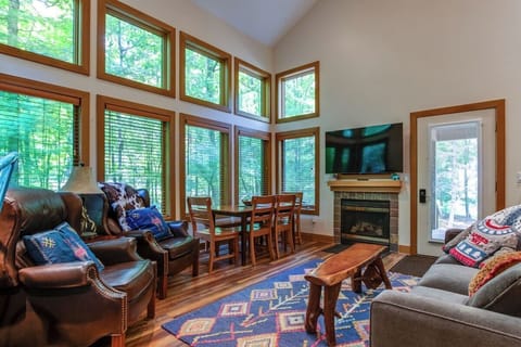 Main living area with flat screen TV, table for 6 and gas fireplace