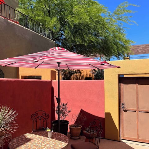 Private walled patio with table, chairs and umbrella.