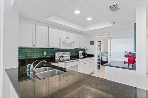 Your fully equipped kitchen features granite countertops, modern appliances, and a charming green tile backsplash—perfect for preparing meals during your stay.