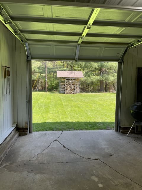 View of back yard from the garage. Firewood is available for purchase onsite.