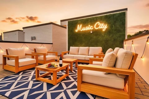 Rooftop lounge with a `Music City` greenery wall, wood patio furniture, and sunset views
