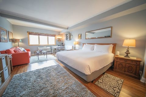 Relax in your spacious bedroom featuring a plush king bed, cozy seating area, and warm wood floors that create the perfect retreat.