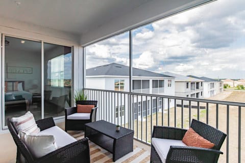 Step onto your private balcony, featuring sleek black wicker chairs and a chic coffee table, perfect for enjoying morning coffee. Large windows bathe the space in natural light, revealing the tranquil surroundings.